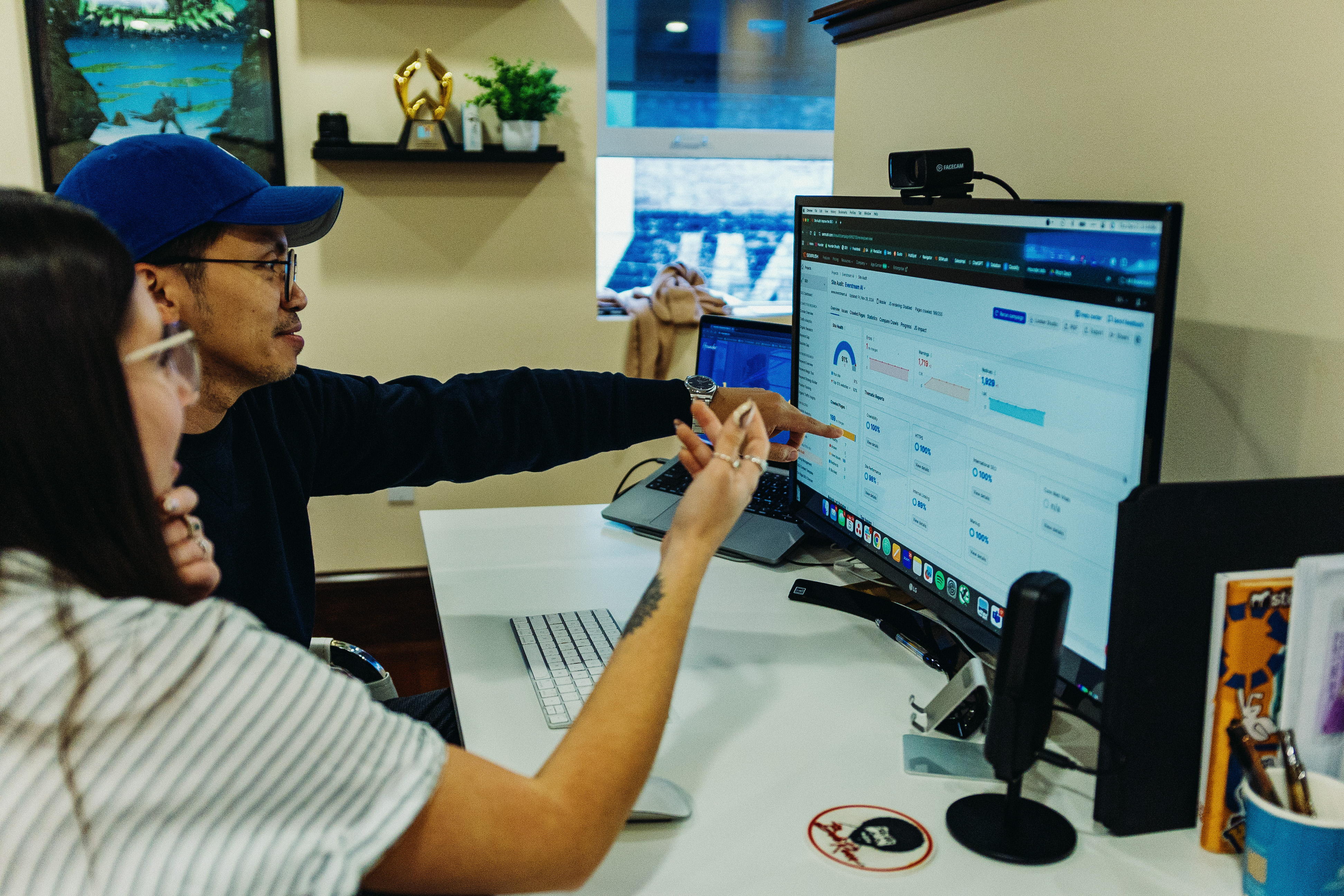 Two people analyzing data on a computer monitor in an office setting.