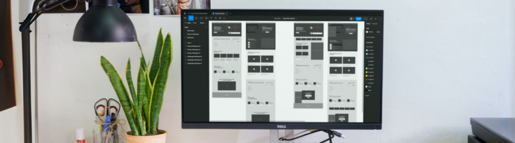 Computer monitor displaying a web design layout near a plant and desk lamp.