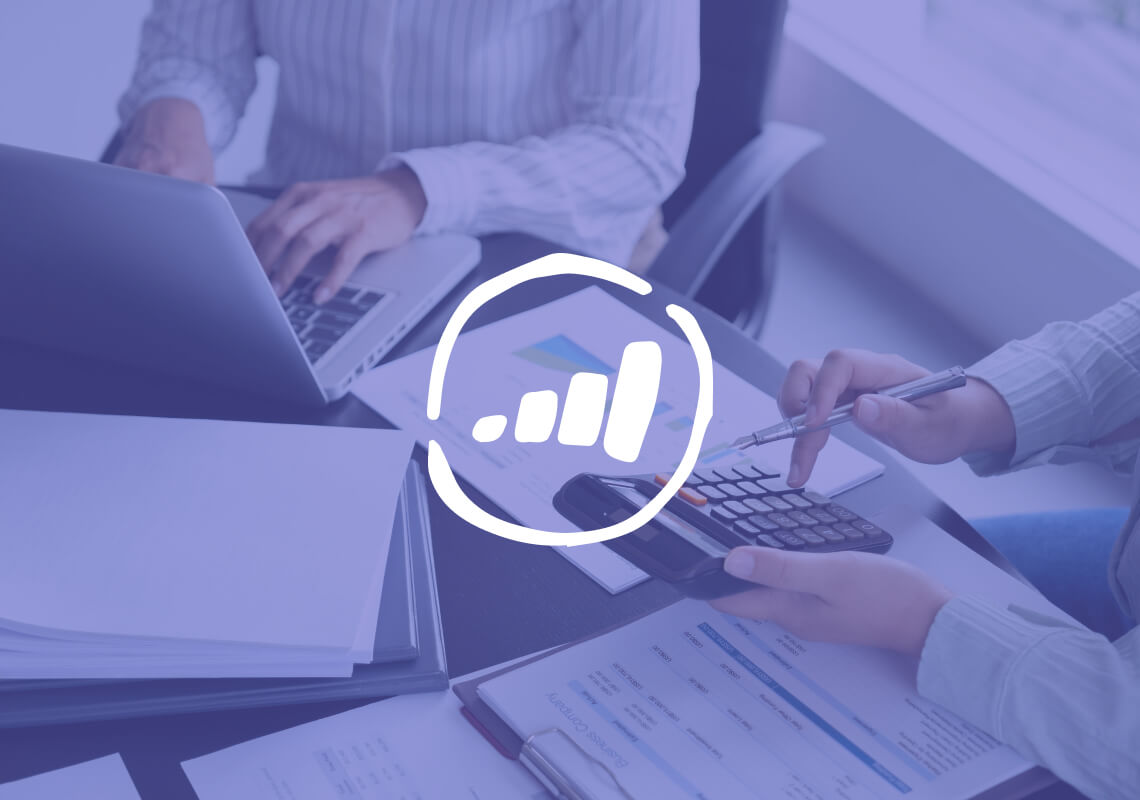 Hands using a calculator and laptop with financial charts.