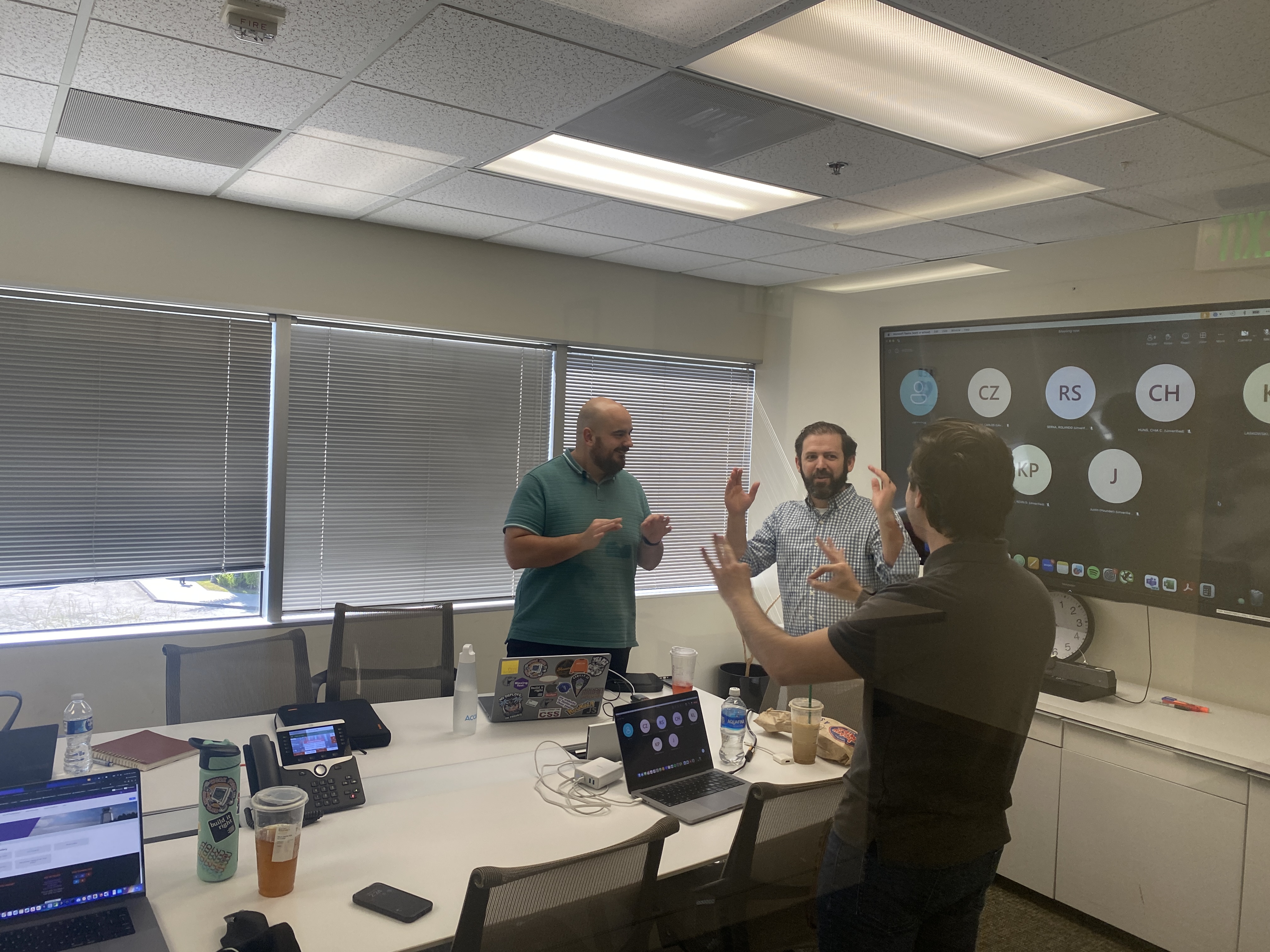 Team collaborating in conference room with a virtual meeting on screen.