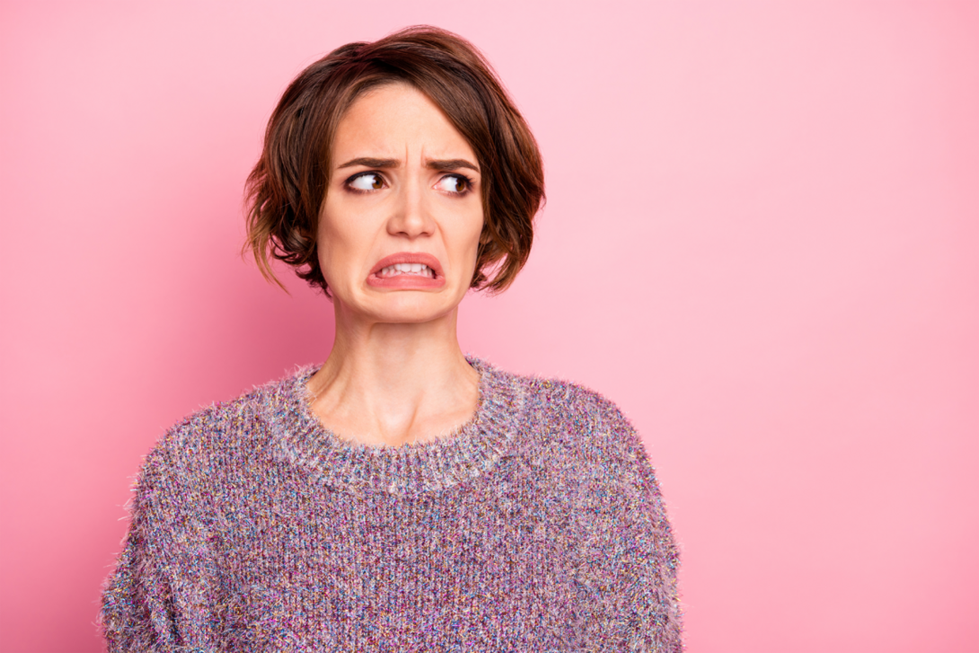 Woman making a disgusted face on a pink background.