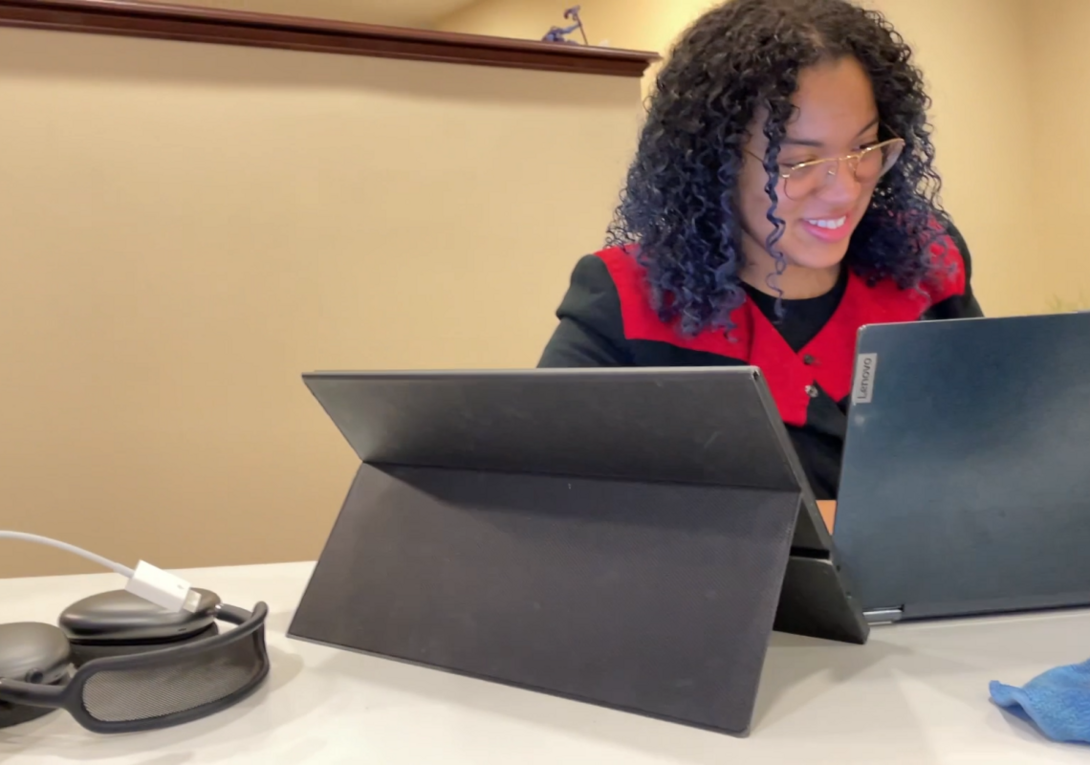 woman seated at a table typing on a computer