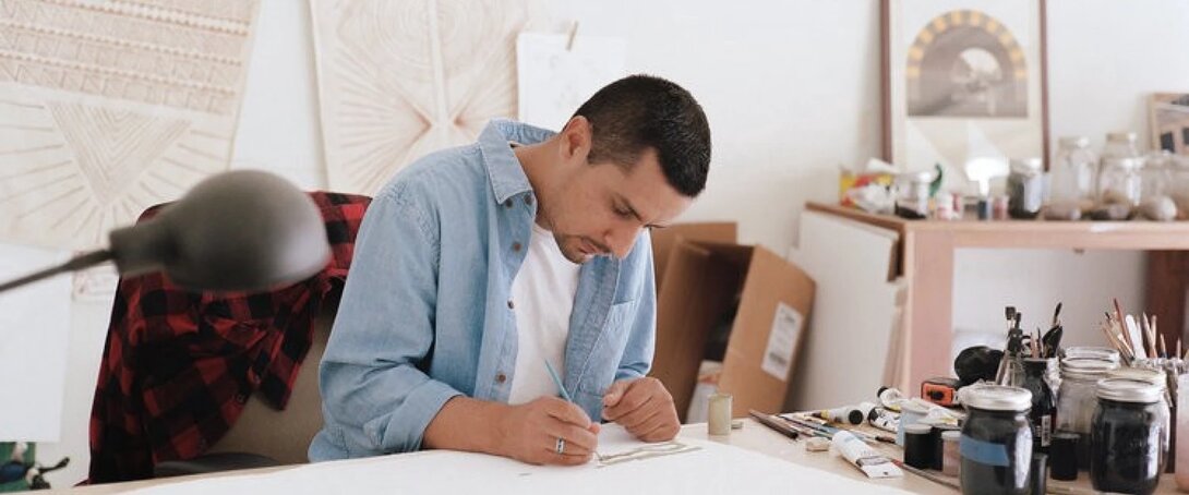Artist focused on drawing in a creative studio setting.