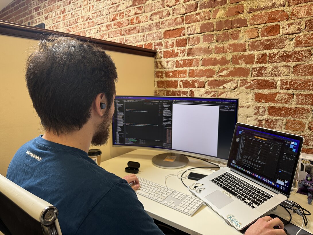 Hounder employee coding on two computer screens