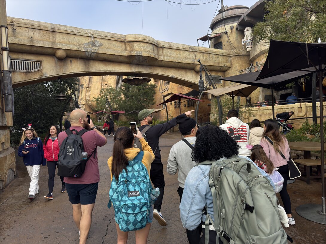 Crowds explore a themed sci-fi park with rustic architecture and detailed scenery.